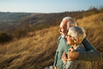 Happy mature couple enjoying while spending an autumn day on the hill. Focus is on man.