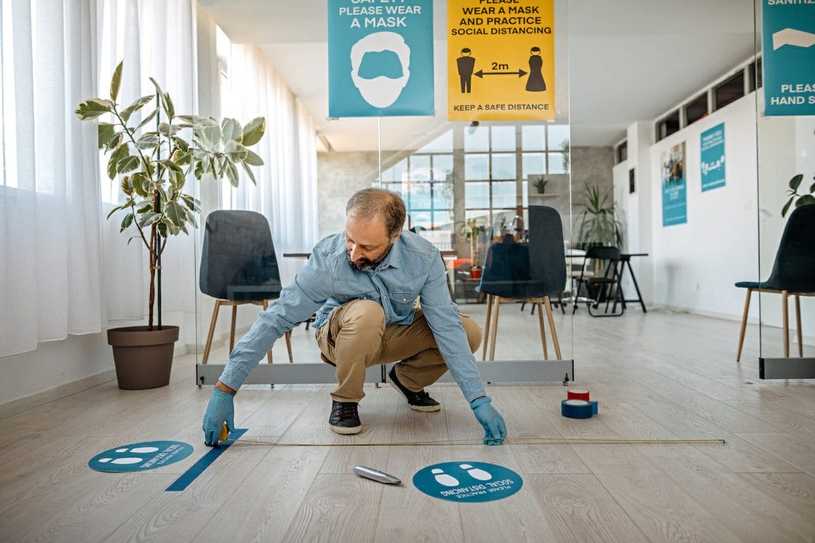 Man applying social distancing sign at office