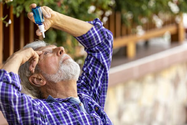 Senior Caucasian man inserting eye-drops
